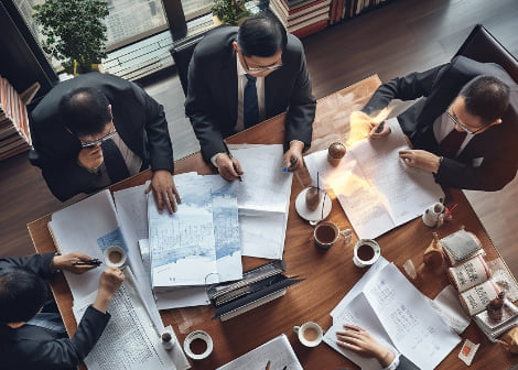 Overhead view of a team working through plans and documents spread across a table.