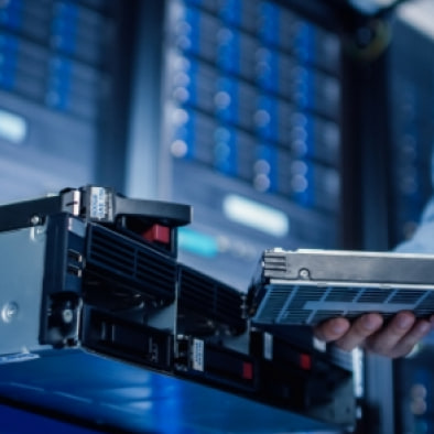 A technician sliding a drive module out of a rack-mounted server.